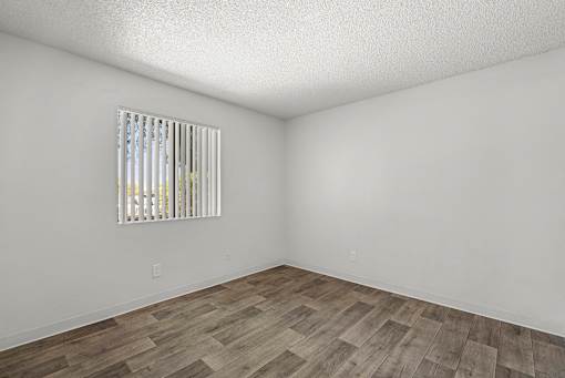 A room with a window and wooden flooring.