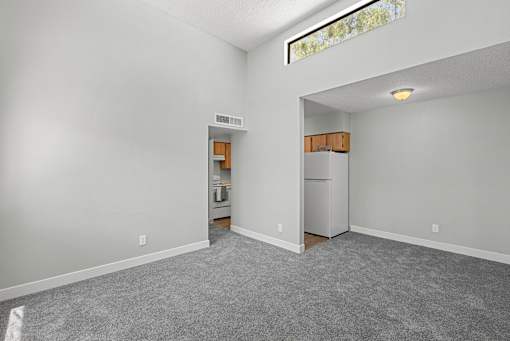 A room with a kitchenette in the other room.