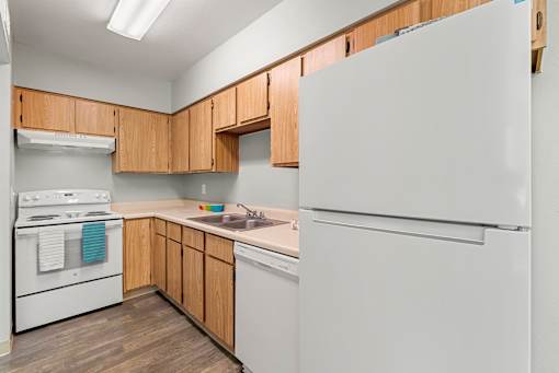 A kitchen with white appliances and wooden cabinets.