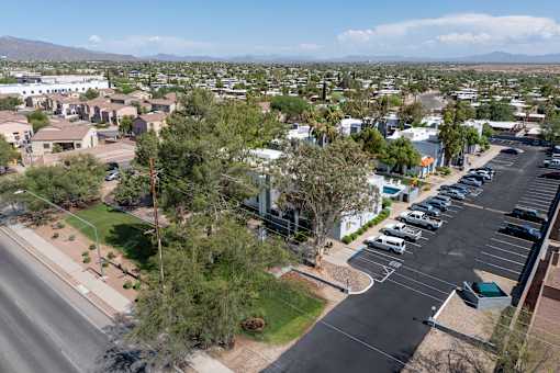 A parking lot with cars and a road in front of a residential area.