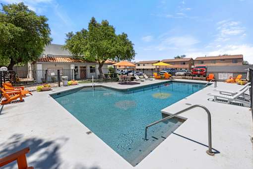 A swimming pool surrounded by a concrete patio and trees.