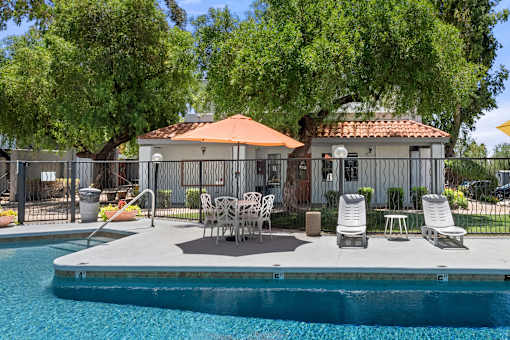 A pool with a patio and chairs.