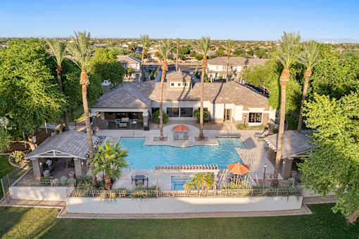A large house with a pool surrounded by palm trees.
