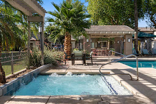 A pool with a waterfall and a hot tub in a backyard.