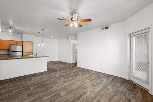 A room with a ceiling fan and wooden flooring.