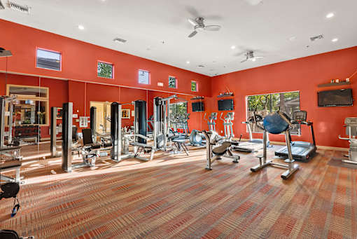 A gym with a variety of equipment including treadmills, weights, and exercise machines.