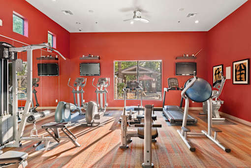 A gym with a variety of equipment including treadmills, weights, and exercise machines.