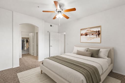 A bedroom with a large bed and a ceiling fan.
