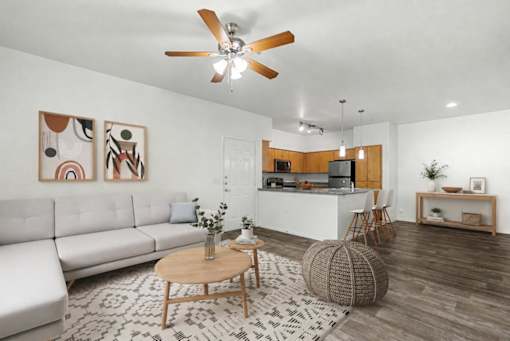 A living room with a white sofa, a wooden coffee table, and a ceiling fan.