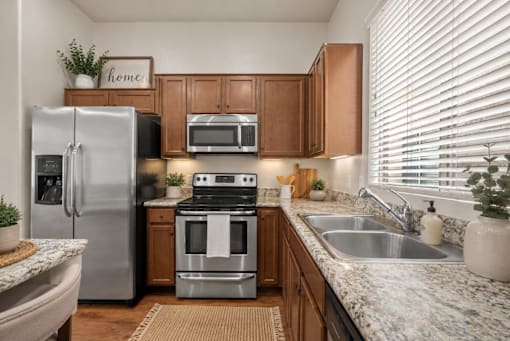 A kitchen with a refrigerator, oven, and sink.