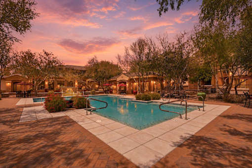 A pool surrounded by trees and a building in the background.