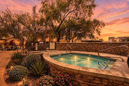 A pool surrounded by a stone wall and plants.