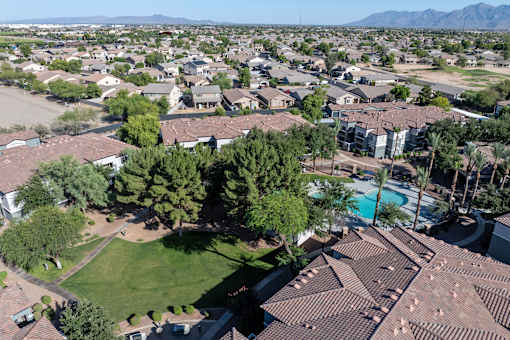 A bird's eye view of a residential area with houses, trees, and a pool.