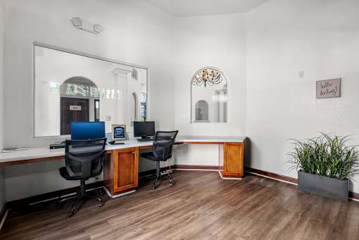 A room with a desk, chairs, and a mirror.