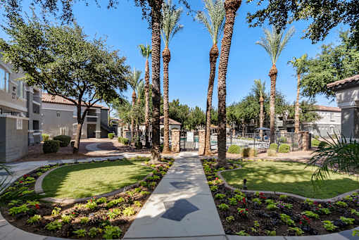 A pathway leads through a landscaped area with palm trees and shrubs.