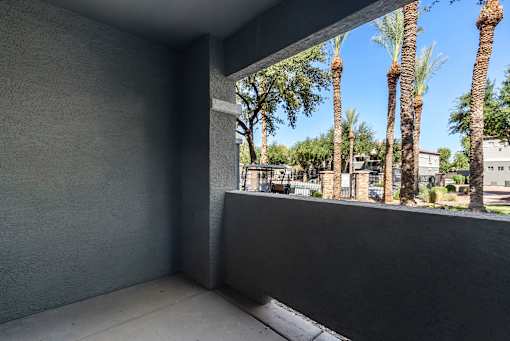 A balcony with a view of palm trees and a blue sky.