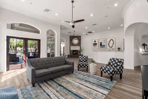 A living room with a grey couch, a black and white chair, and a rug.
