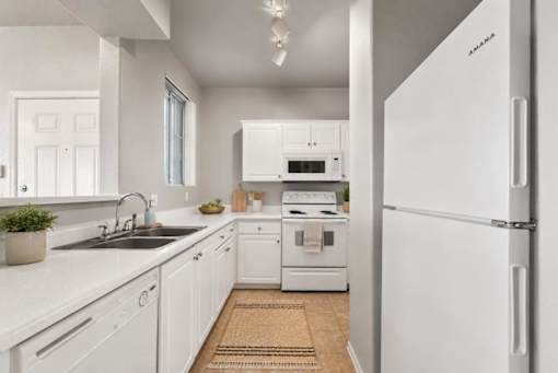 A white kitchen with a sink, stove, and refrigerator.