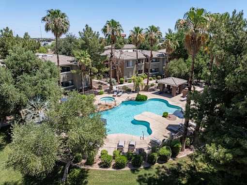 A swimming pool surrounded by palm trees and apartment buildings.