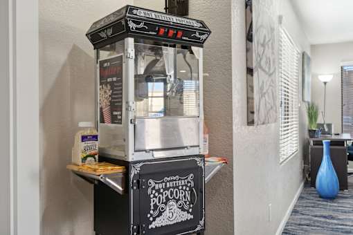 A hot buttered popcorn machine is on a table.