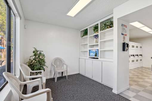 A room with white chairs and a white cabinet with a computer on it.
