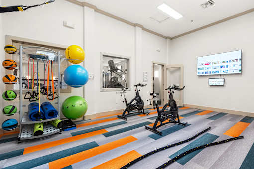 A gym with exercise equipment and a TV screen.