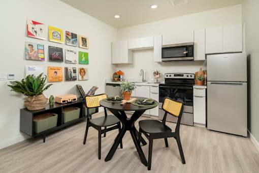 A kitchen with a table and chairs and a fridge.