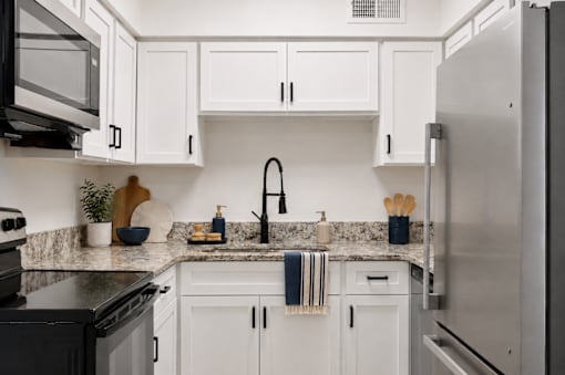 A kitchen with white cabinets and a black stove top oven.