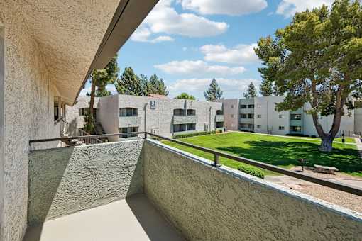 A view from a balcony looking out at a courtyard with a tree.