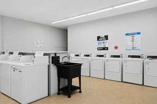 A room with a black desk and white washing machines.