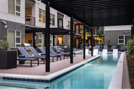 A pool area with lounge chairs and a building in the background.