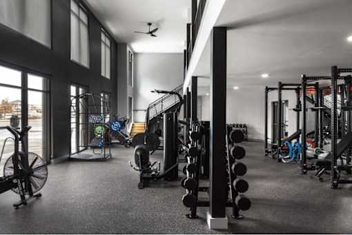 A gym with a variety of equipment including weights and a fan.