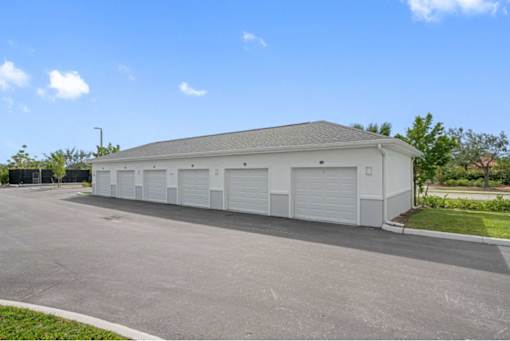 A large white building with a grey roof and multiple garage doors.