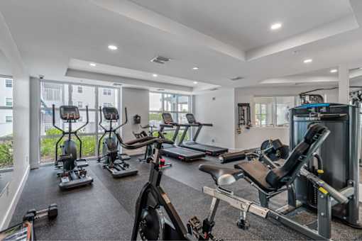 A spacious gym with a variety of equipment including treadmills, stationary bikes, and weight machines.