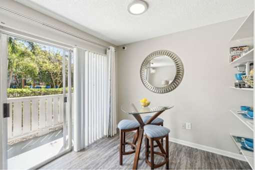 A dining area with a table and chairs and a mirror on the wall.