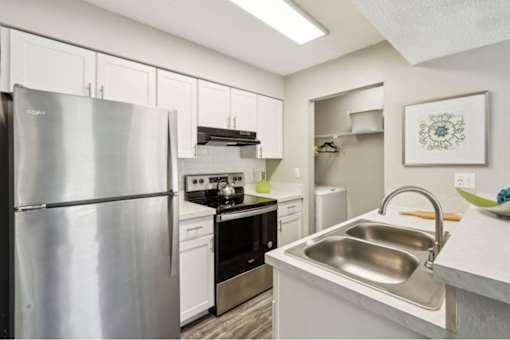 A modern kitchen with a stainless steel refrigerator and a stainless steel sink.