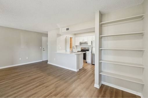 A kitchen with white cabinets and a wooden floor.