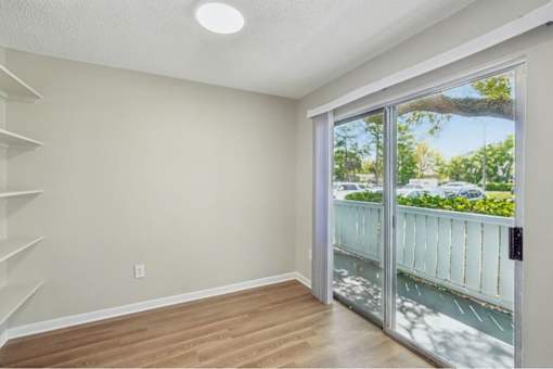 A room with a staircase and sliding glass doors leading to a balcony.