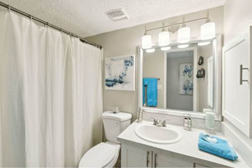 A white bathroom with a toilet, sink, and shower curtain.
