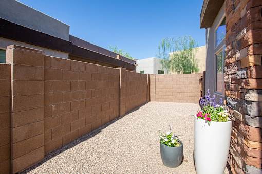 A patio with a wall, a potted plant and a planter.
