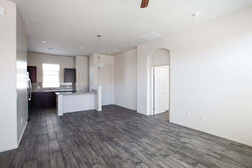 A spacious living room with a kitchen in the background.