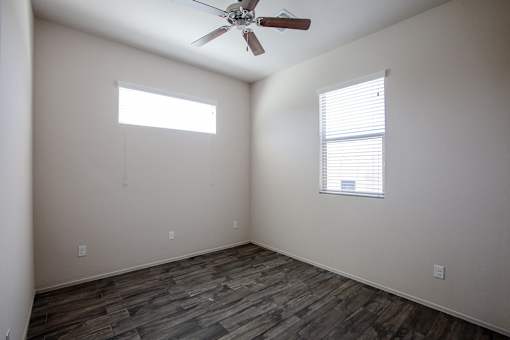 A room with a ceiling fan and a window with blinds.