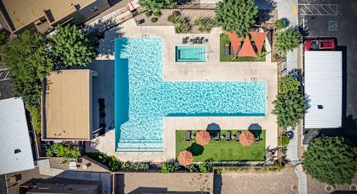 An aerial view of a pool surrounded by trees and a building.