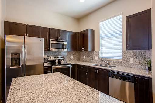 A kitchen with a granite counter top and stainless steel appliances.
