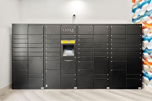 A wall of black lockers with one open and a yellow sign on it.