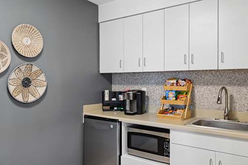 A kitchen with a microwave, refrigerator, and sink.