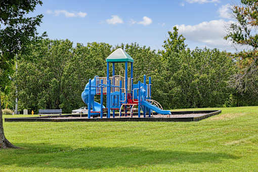 A playground with a blue slide and a green roof.