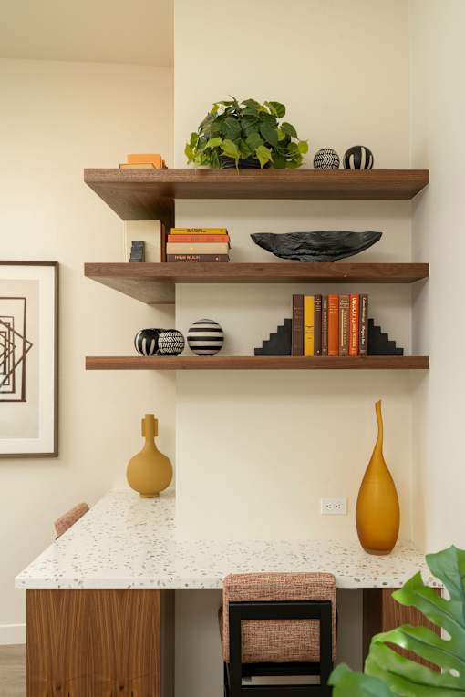 A kitchen with a white counter top and a wooden shelf above it.
