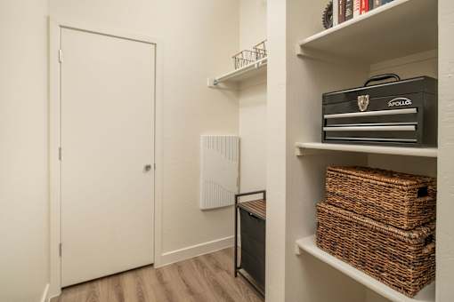 A white door is on the left and a shelf with baskets and a box is on the right.