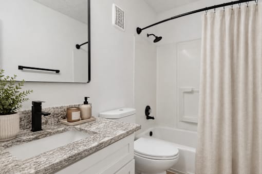 A white bathroom with a sink, toilet, and shower.